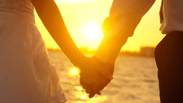 couple holding hands sunset