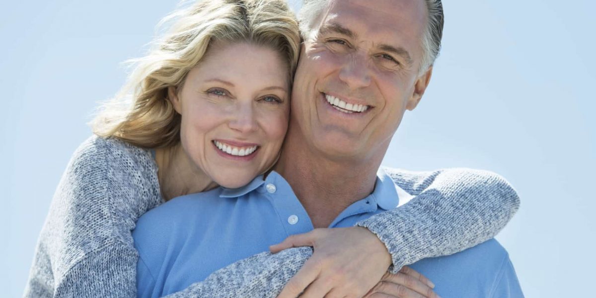 Loving Woman Embracing Man From Behind Against Clear Sky Portrait of loving mature woman embracing man from behind against clear blue sky
